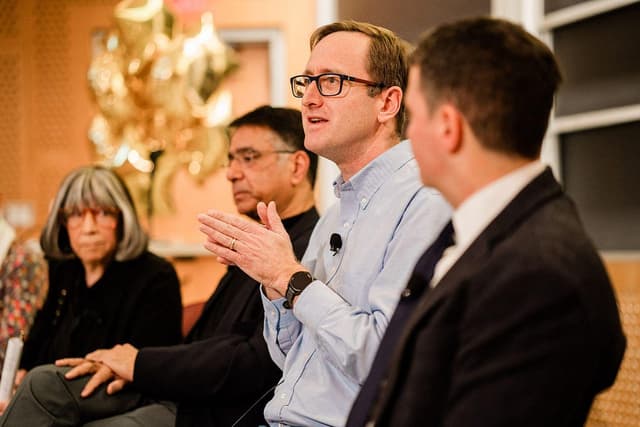 Side view of four people seated on a panel.