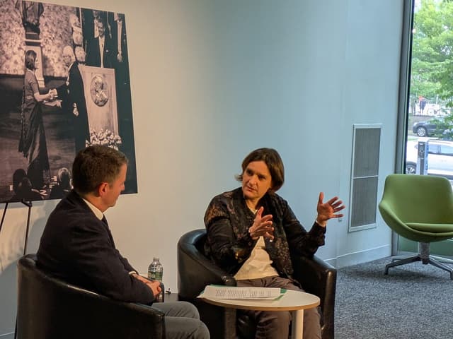 Candid photo of a woman in business casual attire speaking animatedly to a man during a panel.